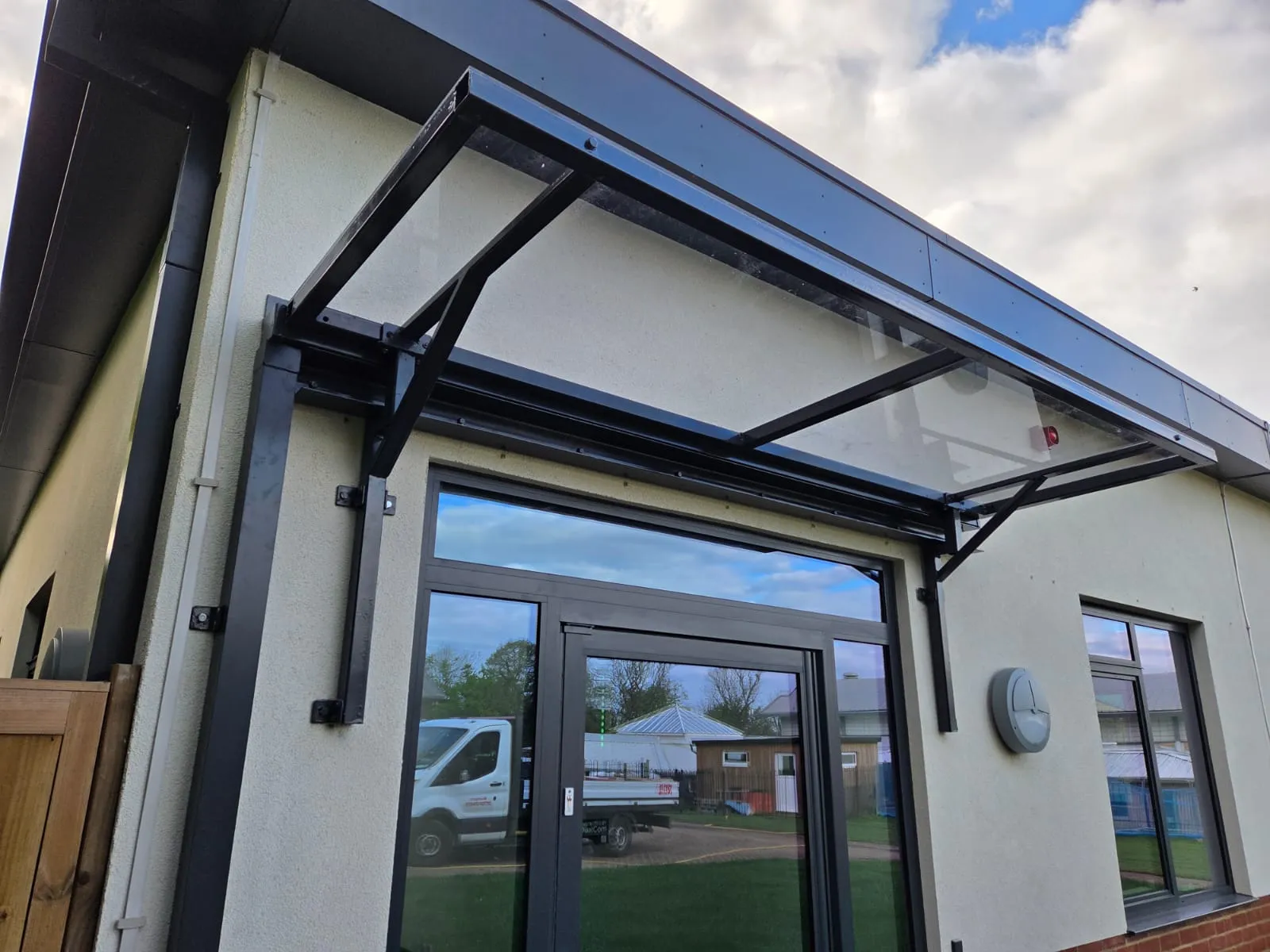 Steel-framed glazed entrance canopy over a commercial building's side door